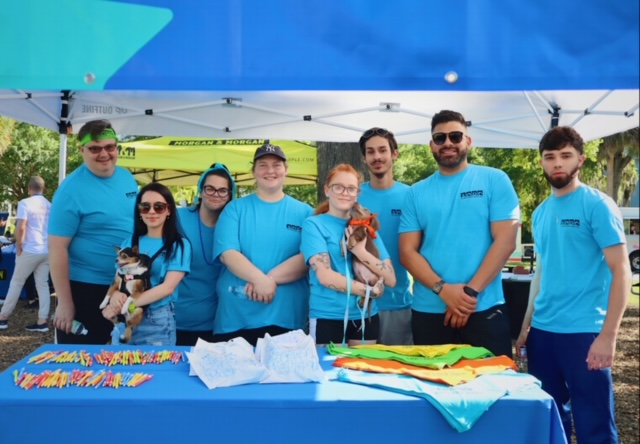 Team members from SODO Veterinary Hospital in Orlando, Florida standing together at an outdoor event wearing blue t-shirts and holding their pets. 